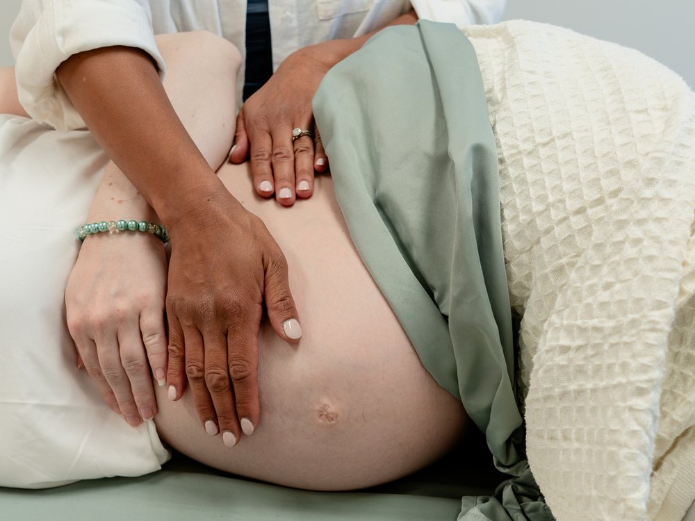 Hands resting on a pregnant client's belly during treatment Hands resting on a pregnant client's belly during treatment